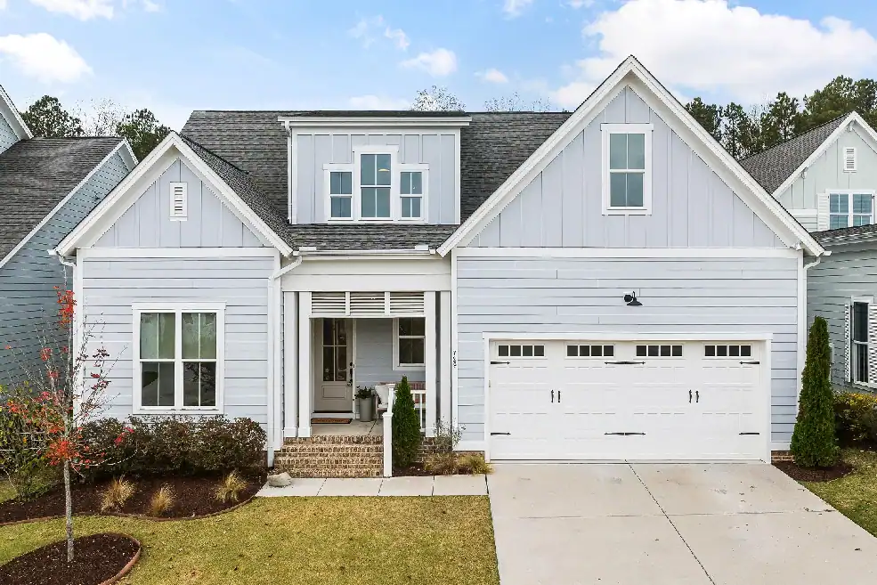 Gray suburban home with a white double garage door and concrete driveway.