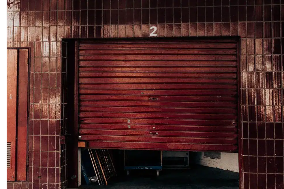 Partially open metal rolling door at a garage entrance